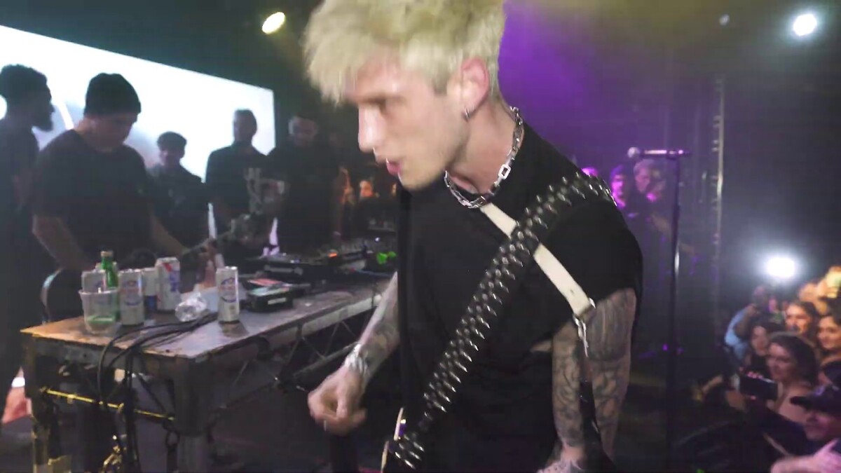 Machine Gun Kelly memainkan gitar saat tampil bersama Travis Barker di atas panggung.